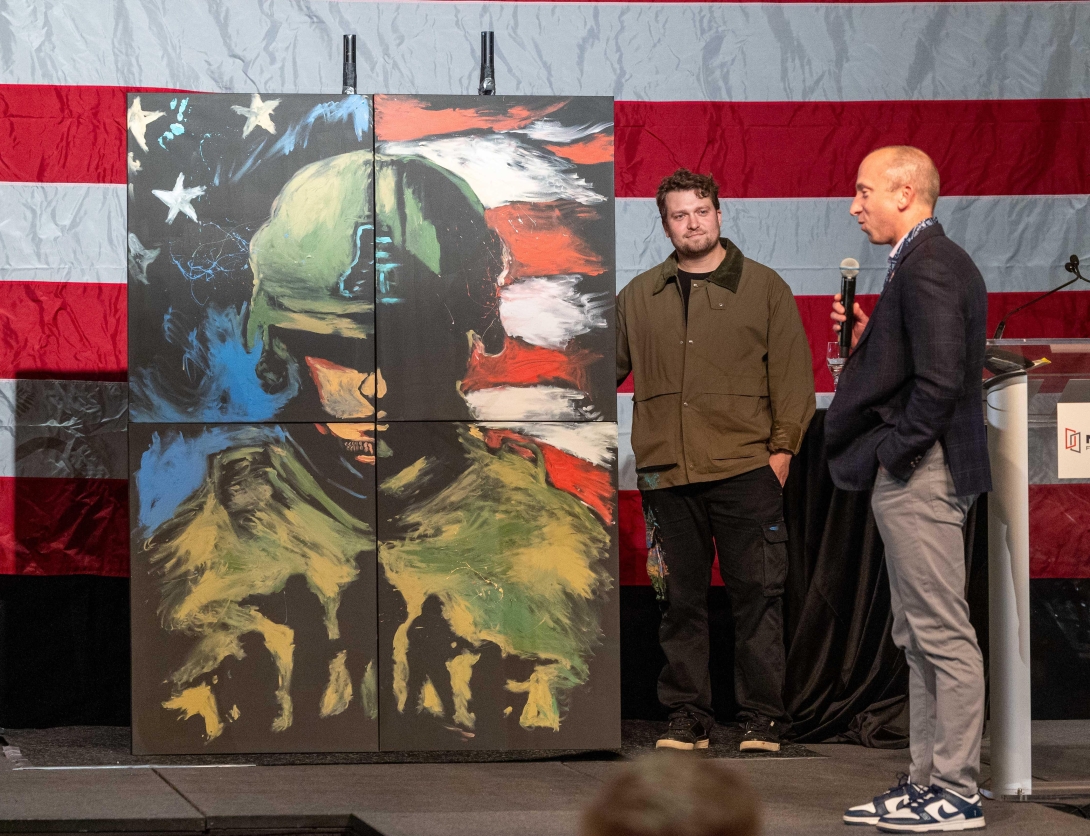 Matt DeSoto, MITER Brands CEO, touts speed painter Cody Sabol’s artwork during the live auction at the Scottsdale golf outing.